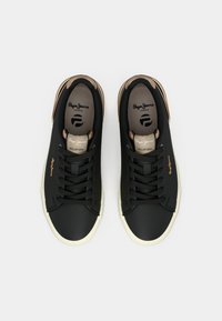 Melni sporta apavi ar gludu augšu, apaļu purngalu un krēmkrāsas gumijas zoli. Aprīkoti ar zelta akcentiem un teksturētām auklām. Logotips redzams uz mēles.