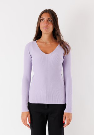 Top lungo a maniche con coste di colore lillà, design a V, caratterizzato da una silhouette aderente e un tessuto testurizzato. Indossato con pantaloni neri.