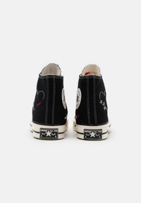 Schwarze High-Top-Sneaker aus Canvas mit weißer Naht. Mit dem ikonischen runden Abzeichen, Herz-Stickerei und Gummisohle mit Markendetails.