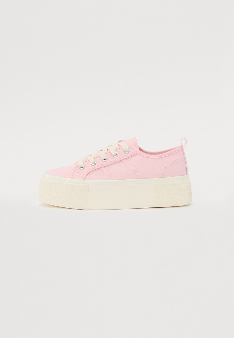 Roosa kangast platvormsneakerid tekstureeritud valge tallaga, lame pael ja külgmised triibud. Omab tagaosa aasat mugavaks jalga panemiseks.