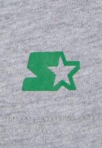 Grått stoff med en strikket tekstur som har en grønn logo bestående av et stilisert bokstav "S" og en stjerne.