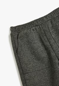 Pantalones jogger de tejido gris con cinturilla elástica, bolsillos laterales y tela texturizada que muestra patrones sutiles con un acabado suave.