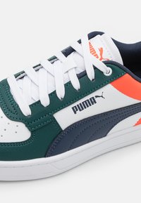 Lærresko i grønn, marineblå og hvit med oransje detaljer. Har hvite lisser, perforert tåpanel og en fremtredende Puma-logo.