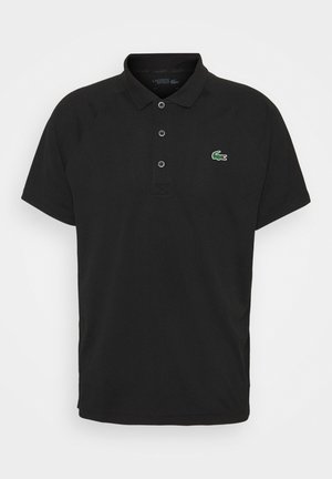 Camisa polo negra hecha de una tela transpirable, con un cierre de dos botones, mangas cortas y un logo de cocodrilo verde en el pecho.