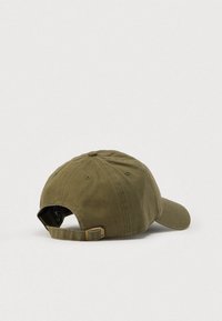 Λαδί βαμβακερό καπέλο με κυρτή γείσο, ρυθμιζόμενο λουράκι στο πίσω μέρος και ραμμένες τρύπες αερισμού στα πάνελ. Υφή υφάσματος με ανάγλυφη επιφάνεια.