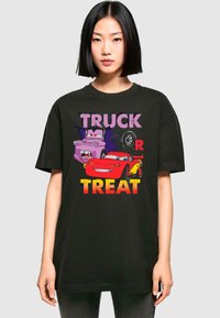 Juodas marškinėliai su "Truck or Treat" grafika ir animaciniais automobiliais. Ryški, spalvinga tekstūra tamsiame fone, trumpomis rankovėmis.