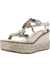 Sandalia de cuña beige con suela de yute tejido, adornada con strass transparentes y negros en la parte superior de ante. Diseño de puntera abierta con correa en el tobillo.