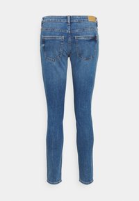 Jeans skinny feitos de denim de lavagem média, com uma cintura de altura média, dois bolsos traseiros e um patch de couro com a marca na cintura.