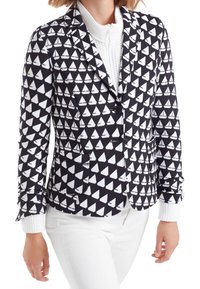 Blazer en blanco y negro con un patrón de veleros, cierre de un solo botón, solapas con muesca y puños de punto blancos. La tela parece suave.