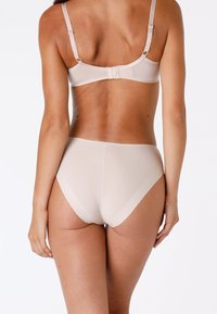 Set di lingerie beige composto da un reggiseno liscio con spalline regolabili e culotte a vita alta, che mette in risalto un design senza cuciture e una texture morbida.