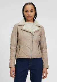 Beige jasje van nep leer met een sherpa kraag, ritssluiting aan de voorkant, steekzakken aan de zijkant en een aansluitend model. Getextureerd oppervlak met duidelijk zichtbare naden.