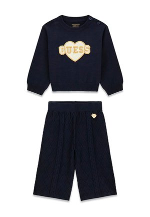 Marineblå strikket sweater med hjerte og "GUESS" logo kombineret med matchende quiltede marineblå bukser med lille hjerte-detalje.