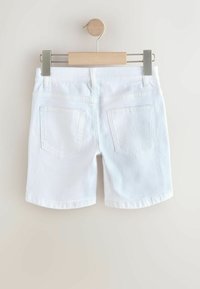 Hvide denimshorts med en klassisk pasform, der har to baglommer og en glat overflade. Hængt op på en træbøjle med metalclips.