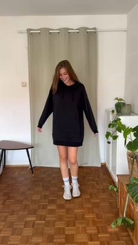 Svart hoodiekjol med en känguruficka, justerbara dragsnören och ribbad nederkant. Bärs med vita sneakers och lätta strumpor.