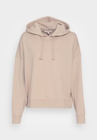 Overdimensionowana beżowa bluza z kapturem, wykonana z miękkiego materiału, z przodu z sznurkiem do regulacji i ściągaczami na rękawach. Prosty design bez wzorów czy akcentów.