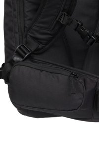 Czarny plecak z nylonowego materiału, regulowanymi paskami i boczną kieszenią na zamek. Charakteryzuje się teksturowaną powierzchnią i trwałymi elementami metalowymi.