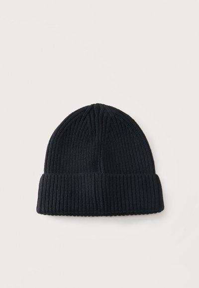Bonnet en tricot côtelé noir avec revers plié, présenté sur un fond blanc uni.