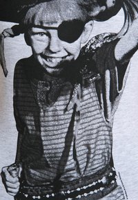 Sort-hvid grafisk tryk af et barn i piratkostume, iført en øjenklap og holdende et sværd, på en lysegrå skjorte.