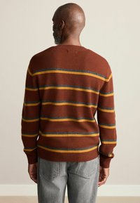 Brown striped sweater with yellow and blue lines. Made from soft fabric, it features a crew neckline and ribbed cuffs and hem.