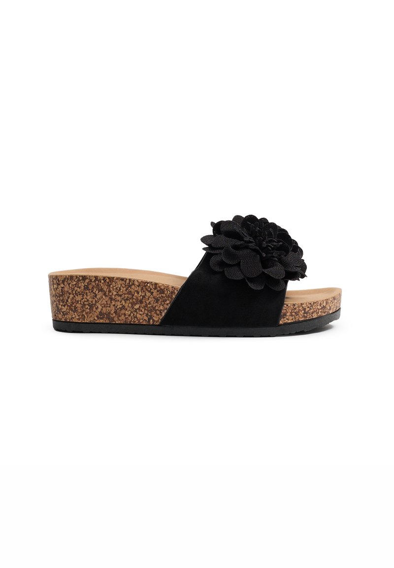 Las sandalias de slide negras presentan una gran flor de tela en la correa, una plantilla de corcho y una suela de goma plana para ofrecer agarre. Parte superior de suave ante.