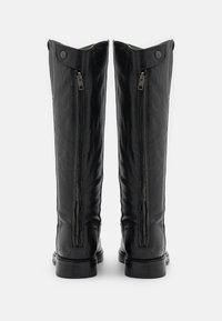 Une paire de bottes en cuir noires montantes avec des zippers métalliques visibles à l'arrière et des onglets en cuir boutonnés en haut.
