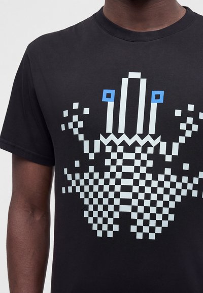 Μαύρο t-shirt με σχεδιασμό pixelated σκακιέρα που μοιάζει με στυλιζαρισμένο στέμμα σε λευκό και μπλε μπροστά.