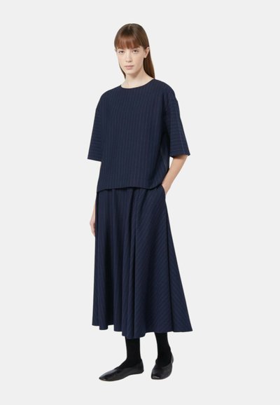 Completo navy a due pezzi con una maglietta boxy a maniche corte e una lunga gonna fluente; presenta righe verticali e una vestibilità comoda.