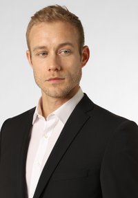 Schwarze Anzugjacke mit Revers, getragen über einem weißen Button-Up-Hemd. Glatte Stoffstruktur, maßgeschneidertes Design mit einer Brusttasche.