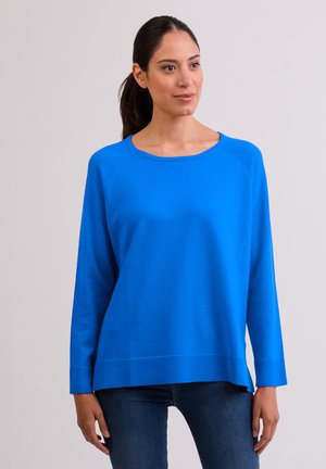 Maglione a maniche lunghe di un blu brillante, realizzato in tessuto morbido, con scollo rotondo e orlo a costine. Indossato con jeans scuri, mostra una vestibilità rilassata.
