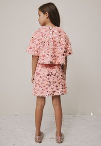 Pink sequin top and skirt set with a textured, fluffy design. The outfit features short sleeves and a round neckline. Sparkly, embellished shoes.