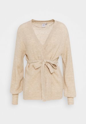 Cardigan enveloppant tricoté beige avec un décolleté en V profond, des manches longues et une ceinture à la taille. Texture douce avec un motif subtil, poignets ajustés et silhouette décontractée.