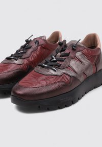 Sneaker rossi e neri con tomaia in pelle testurizzata, punta arrotondata, robusta suola nera e lacci a contrasto, caratterizzati da accenti di design a strati.