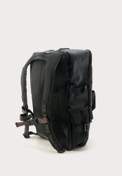 Μαύρο σακίδιο πλάτης με επενδυμένους ιμάντες, πίσω πάνελ από δίχτυ, πλαϊνές τσέπες, ρυθμιζόμενες αγκράφες και λεπτομέρειες ιμάντα με πορτοκαλί κουκίδες, εμφανίζεται από το πλάι.