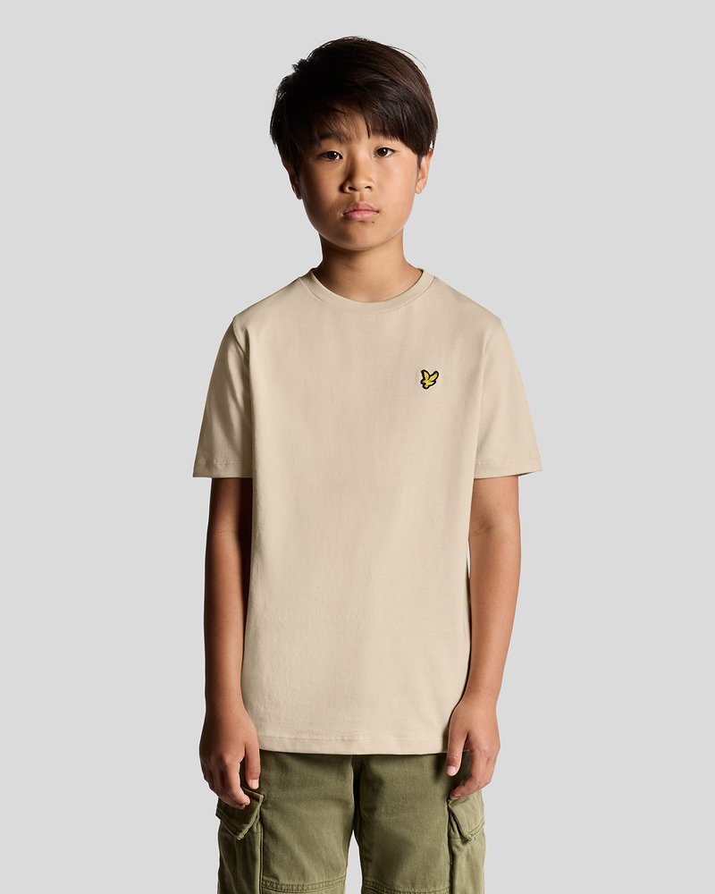 T-shirt en coton beige à manches courtes, avec un petit logo de papillon jaune sur la poitrine gauche, associé à un short cargo vert.