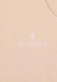 Top smanicato color pesca chiaro realizzato in tessuto morbido con un piccolo logo bianco con la scritta "DISTRETTO" centrato sul davanti.