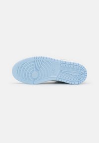Suela de zapatilla Nike, que presenta un material de goma azul claro con patrones circulares y lineales texturizados para un mejor agarre. Diseño limpio, detalles mínimos.
