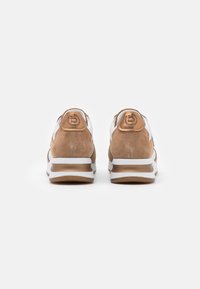 Sneakers marroni e bianchi con suede e pelle liscia. Suole bianche con un accento bronzo, con logo sul retro. Forma arrotondata.