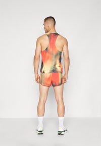 Débardeur sans manches et short pour hommes dans un dégradé d'orange, rouge et noir. Présente une texture en maille avec des accents contrastants et une coupe athlétique.