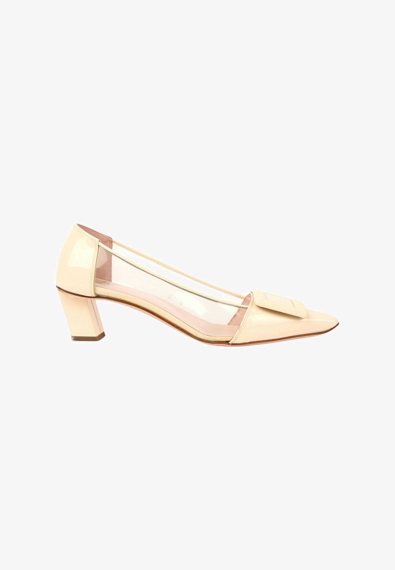 Chaussure femme beige à talon bas, bout pointu, panneaux latéraux transparents, avec une bride décorative beige assortie sur le dessus.