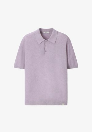 Polo violet clair à manches courtes, avec une patte à trois boutons et une petite étiquette blanche sur l'ourlet inférieur.