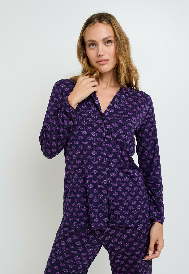 Set di pigiami viola composto da una maglia con bottoni, scollatura a V e maniche lunghe, decorato con un motivo floreale nelle tonalità di rosa e viola.