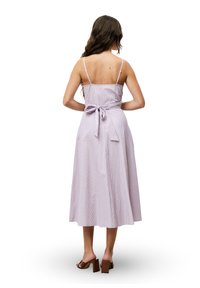 Lila gestreepte jurk met verstelbare spaghettibandjes, een getailleerde bodice en een vloeiende midi-lengte rok. Voorzien van een gestrikte strik op de rug.
