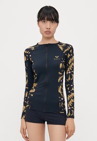 Roxy long-sleeve swim top in navy with a zip front. Features gold and beige abstract pattern, fitted design, and soft, stretchy fabric.