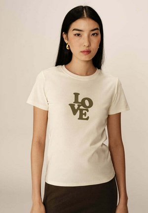 T-shirt à manches courtes couleur crème avec un graphisme "LOVE" vert. Tissu doux avec une coupe décontractée et un col rond.