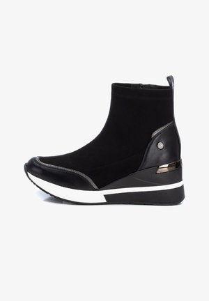 Bottine noire à talon compensé, semelle blanche en accent, fermeture éclair latérale et détail métallique sur le talon ainsi que sur l'emblème du logo latéral.