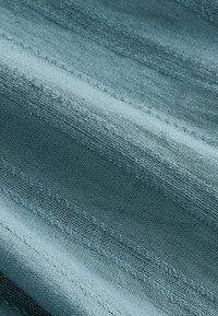 Gros plan sur un tissu bleu avec des rayures horizontales alternant entre lisse et texturé, créant un motif subtil.