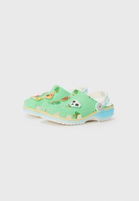 Grüne Clogs aus strukturiertem Material mit bunten Tiermotiven und einem hellblauen, wellenförmigen Akzent um die Sohle.