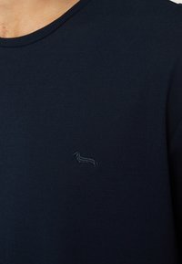 Camicia a maniche corte di colore blu navy con una texture a coste, caratterizzata da un piccolo design ricamato di un bassotto dello stesso colore sul lato sinistro del petto.