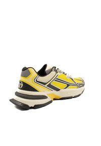 Scarpa sportiva con tomaia in mesh grigia e gialla, dettagli neri, suola testurizzata e tallone imbottito per supporto. Il design include strisce a contrasto.
