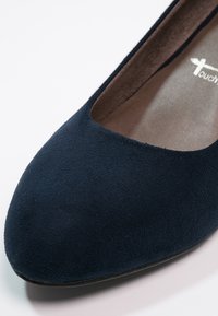 Chaussure plate en daim bleu marine avec bout rond et design profilé bas, dotée d'une doublure intérieure lisse et d'une semelle en caoutchouc plate.